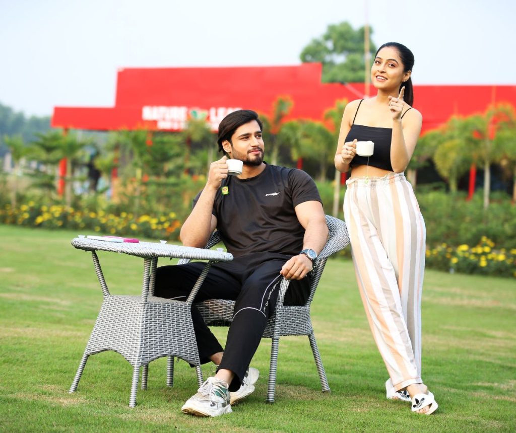 A man and a woman enjoying coffee together in a lush garden, surrounded by greenery, relaxing and unwinding at The Natureland eco resort."