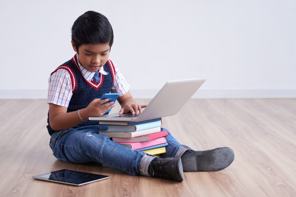 a kid using phonenand laptop